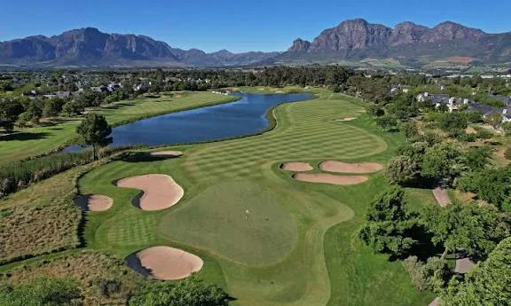 Aerial view of a golf hole with manicured turf, lake and bunkers